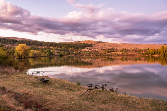 Carp fishing rods with carp bite indicators and reels set up on rod pod near lake river. Fishing during sunset.