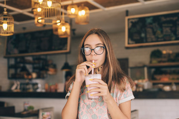 Teen girl drinking smoothie in cafe