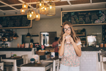 Teen girl drinking smoothie in cafe