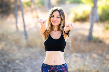 Young sport girl at outdoors points finger at you while smiling