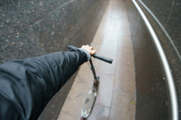 Photography of a man holding city push scooter. Rainy autumn day. Concepts of healthy lifestyle. Fish eye technique/ lens.