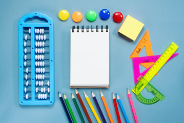 Blank page notebook and school accessories on blue flat lay background. Back to school.