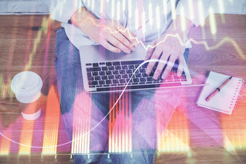 Double exposure of businessman's hands with laptop and stock market graph background. Concept of...
