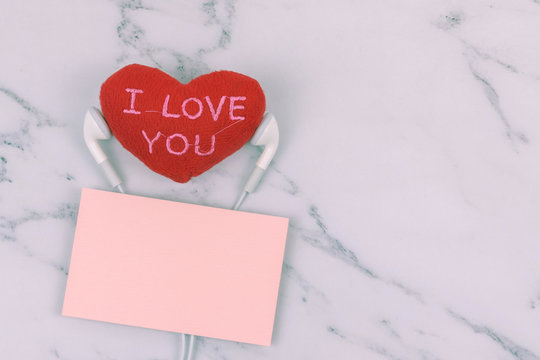 Red heart "I LOVE YOU" use headphone with orange note on white marble background with copy space. Concept of couple, lover, music, melody, relax, romance and Valentine. Love photo.