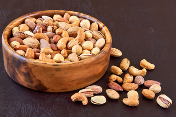 Roasted salted mixed nuts in wooden bowl. Closeup