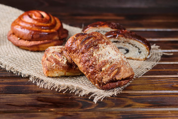 puff buns with jam and raisins in the shape of a snail on burlap and wooden background. Close-up