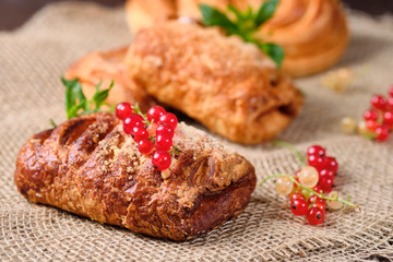 puffs with berry filling with sprigs of fresh red and white currants on burlap and dark wooden background. Close-up. Selective focus