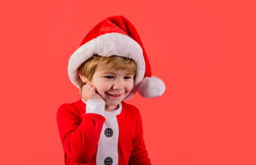 Happy boy in Santa costume. Smiling boy in Santa Claus hat. Christmas time. Santa helper. Little kid in Santa costume. Merry christmas. Happy New Year. Christmas kid in red hat. New Year's holidays.