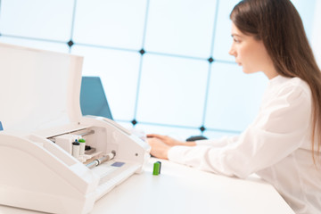 Fototapeta premium Young woman in the office of the printing company sets up a plotter for printing advertising brochures