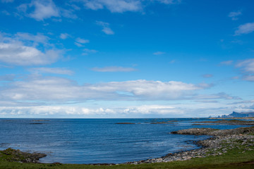 Beautiful nature landscape in North. Scenic outdoors view. Ocean with waves and mountains. Big dark stones. Dramatic storm clouds. Extreme weather, rain and wind. Explore Norway, summer adventure