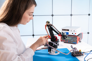A young woman writes an algorithm for the robot arm. Science Research Laboratory for Robotic Arm...