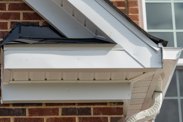 Gable with brick and vinyl siding, white frame gutter guard system, fascia, drip edge, soffit, on a...