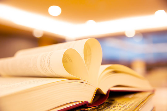 Close up a book image in heart shape on the table at library room concept of lifestyle love to read.