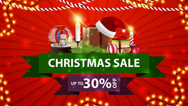 Christmas sale, up to 30% off, red discount banner with ribbonsm snow globe, gift with Santa Claus hat, candles, Christmas tree branch and Christmas ball