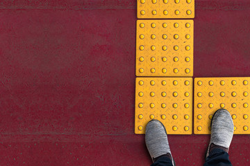 shoes on rough yellow dot tactile paving for blind handicap on tiles pathway in japan, walkway for...