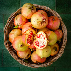 Basket full of pomegranates with a opened one. Fresh fruit from Apulia region, Italy
