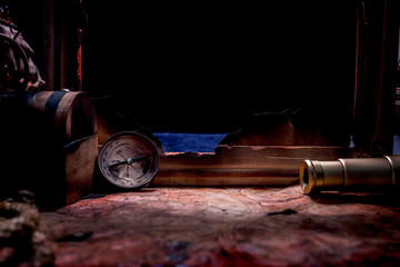 Columbus Day. Pirates and treasure with worldmap and discovery equipment. Copy space on dark...
