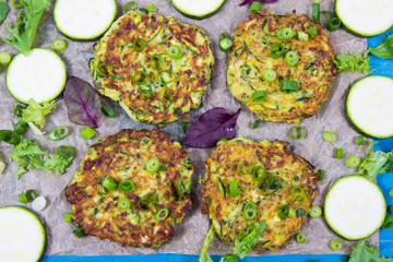Zucchini pancakes with chives on a wooden table.