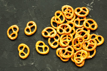 Pretzel with many small cookies scattered on a dark background. View from above. Traditional food for Oktoberfest - salt appetizer pretzels on a black background. German pretzel von, Oktoberfest.