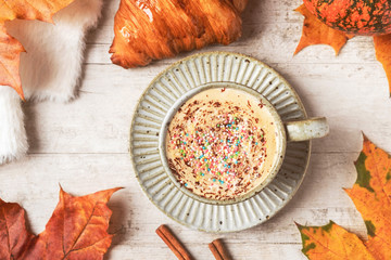 Coffee, croissant, pumpkin, white fluffy sweater on a white background and maple autumn leaves.