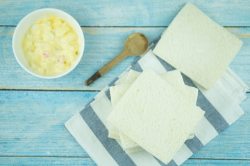 Boiled egg mixed with mayonnaise salad cream in bowl with white bread.