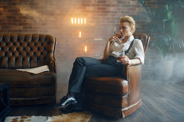 Woman sitting in chair with whiskey and cigar