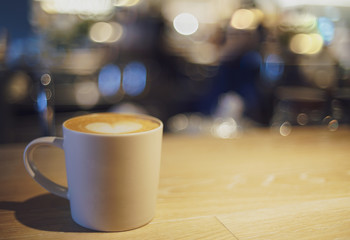 Coffee latte cup on wood table with bokeh light background,  Vintage style
