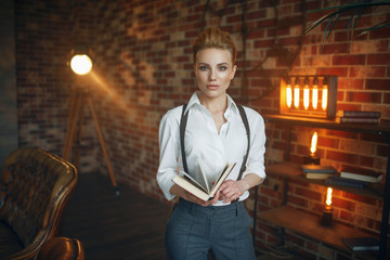 Business woman in strict clothes poses with book