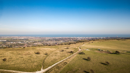 Obraz premium Eastbourne and The South Downs, East Sussex, England. An aerial view of the South Downs Way leading towards the popular south coast seaside resort.