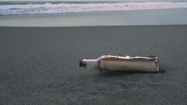 瓶に入った手紙が夕暮れの浜辺に漂着しているイメージ