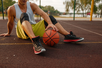 Basketball player with ball sitting on the ground