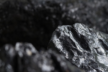 Black coal mine close-up with soft focus. Anthracite coal bar on dark background. Natural black coal bars for background. Industrial coal nuggets close up