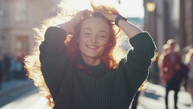 Gorgeous happy ginger young woman walking in the street smiling having positive mood enjoying sunlight spring weather. Unique female beauty.