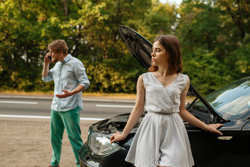 Couple calling a tow truck on road, car breakdown