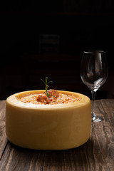 Italian shrimp risotto served inside a big Parmesan Cheese Wheel on a wooden background