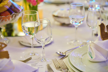 Table setting for guests in a restaurant, on the table forks and glasses for wine - flowers in a vase and a candle on the table