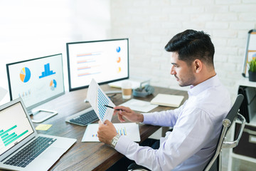Attractive Young Male Sales Professional Analyzing Chart