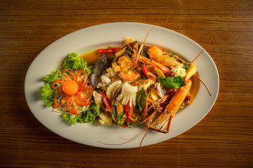 Stir​ fried​ spicy seafood in​ the​ white​ plate.