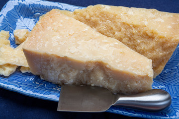 Italian original aged Parmesan cheese in two pieces served on blue plate close up