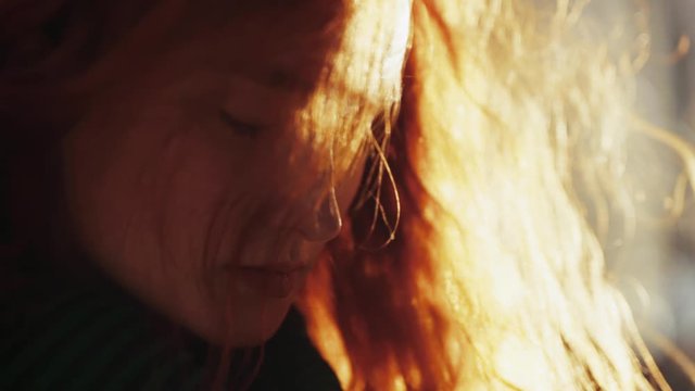 Gorgeous adorable young ginger woman with eyes closed meditating in bliss feeling the wind blowing her hair. Female portrait. Close-up.
