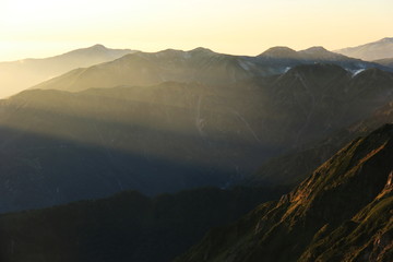 北アルプス　槍穂高大キレット縦走　南岳山頂からの風景　夕陽の光芒と笠ヶ岳のシルエット