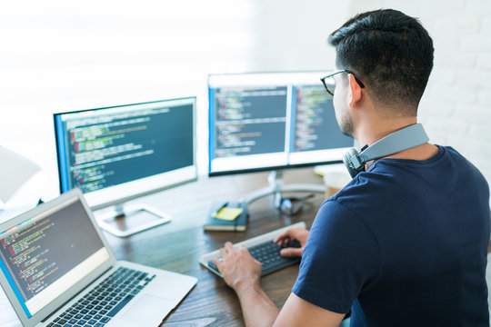 Hispanic Male Programmer Coding At Desk