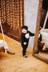Vertical portrait of baby boy and big mirror. Beautiful little man celebrates New Year