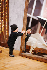 Obraz na płótnie Canvas Vertical portrait of baby boy and big mirror. Beautiful little man celebrates New Year