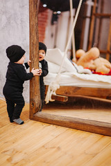 Vertical portrait of baby boy and big mirror. Beautiful little man celebrates New Year