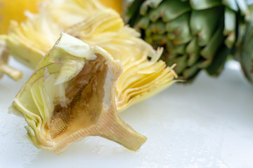 Preparation of heads of fresh raw artichokes plants from artichoke plantation in Argolida, Greece ready to cook with lemon
