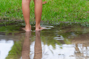 The child's legs on the flooded water and the green grass in the background.