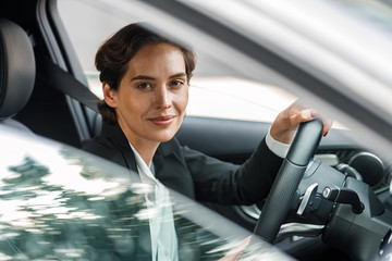 Side view of businesswoman driving car looking out of window. Portrait of a woman going to office...