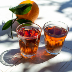 Young rose wine served outside in garden on white table with fresh orange in sun lights