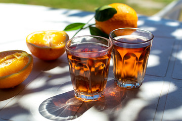 Young rose wine served outside in garden on white table with fresh orange in sun lights